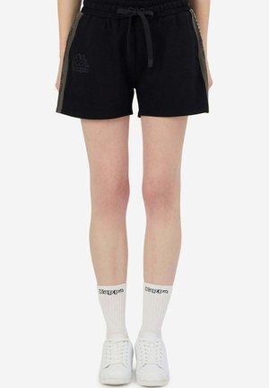 Shorts neri in cotone con vita elastica, cordino, dettagli logo laterali e una vestibilità rilassata. Abbinati a calzini bianchi e sneaker.