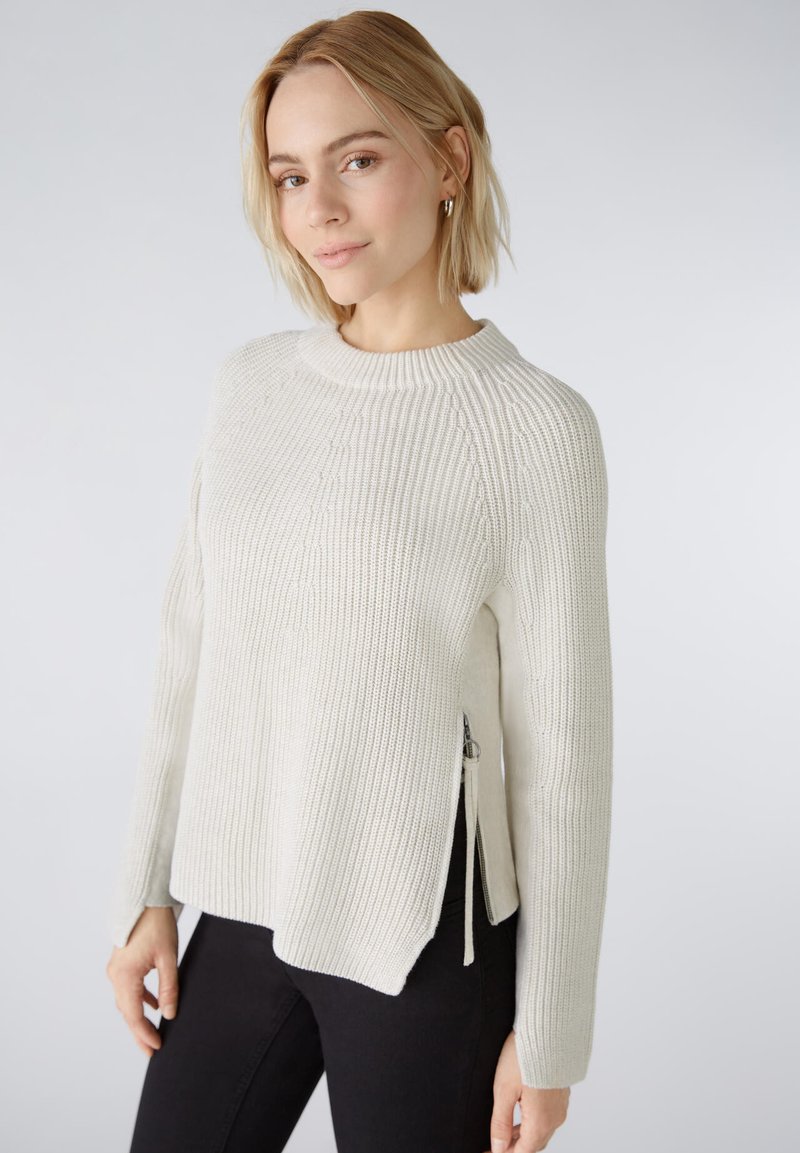 Hellgrauer, gerippter Strickpullover mit rundem Ausschnitt, seitlichen Reißverschlüssen und langen Ärmeln; zeichnet sich durch eine lockere Passform und strukturierten Stoff aus.