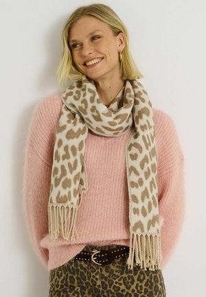 Pañuelo beige con estampado de leopardo y bordes con flecos, colocado de manera suelta alrededor del cuello. Llevado sobre un suéter rosa peludo y pantalones con estampado de leopardo.