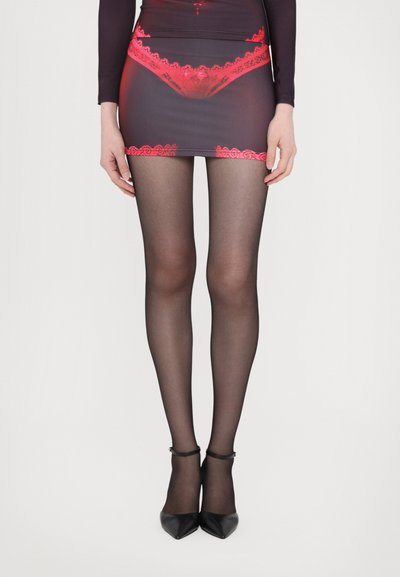 Calze velate nere abbinate a un vestito corto con rifinitura in pizzo rosso. Scarpe nere con tacco alto e punta completano il look.