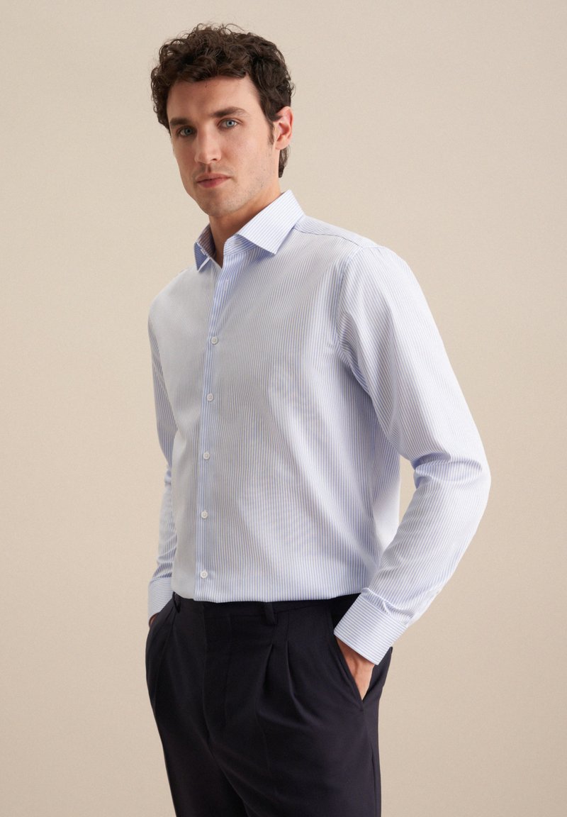 Camicia a righe azzurro chiaro con colletto a punta, maniche lunghe, design classico con bottoni, abbinata a pantaloni scuri.
