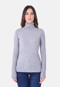 Maglione grigio a collo alto realizzato in morbido tessuto a maglia, con maniche lunghe e design aderente. Abbinato a jeans in denim blu.