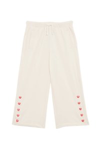 Pantalons larges de couleur crème avec une taille élastique, comportant des poches latérales et des boutons en forme de cœur rose le long de la jambe.