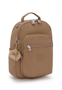 Zaino in nylon marrone chiaro dalla forma arrotondata, con tasca frontale con zip, patch con il logo e un portachiavi a forma di scimmia pelosa attaccato. Accenti in metallo argentato.