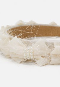 Haarband aus crèmefarbigem Stoff, das mit geschichteten Tüllblüten, Perlenakzenten und zarten Strängen verziert ist, mit einem weichen Innenfutter für zusätzlichen Komfort.