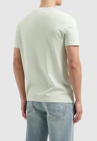 Lichtgroene katoenen t-shirt met korte mouwen, een ronde hals en een eenvoudig ontwerp. Draagt met lichtblauwe denim jeans.