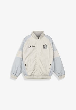 Leichte Jacke in Creme und Hellgrau mit hohem Kragen, elastischen Bündchen und gesticktem Text und Logo auf der Brust.