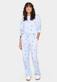 Set di abbigliamento per il tempo libero di colore azzurro chiaro, realizzato in tessuto morbido, con motivi a cuori neri. La parte superiore ha maniche lunghe e i pantaloni presentano una vita elasticizzata.
