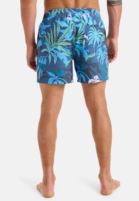 Szorty kąpielowe w ciemnoniebieskim kolorze z tropikalnym wzorem liści w odcieniach zieleni, jasnoniebieskiego i różowego. Elastyczny pas i detal kieszeni z tyłu.