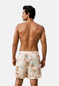 Bañadores de hombre con un patrón floral beige que presenta palmeras y acentos azules, cinturilla elástica y un corte holgado.