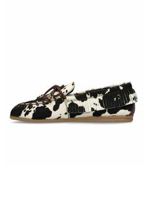 Mocassin en cuir de vache noir et blanc avec lacet en cuir marron et détails de franges sur une semelle plate beige.