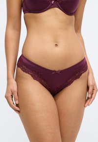 Vīnkrāsas mežģīņu biksītes ar mīkstu auduma pamatni, smalku mežģīņu apdari, mazu loku priekšpusē un piegulošu formu.