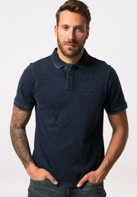Námořnická modrá polo košile vyrobená z texturované tkaniny, s trojicí knoflíků, krátkými rukávy a diskrétním logem na hrudi.