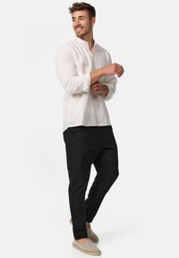 Lettet, langærmet skjorte med knaplukning i off-white, parret med sorte tapered bukser og beige slip-on sko. Glat tekstur, afslappet pasform.