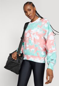 Felpa tie-dye colorata in rosa e menta, realizzata in morbido tessuto. Presenta maniche lunghe, polsini a costine e dettaglio con logo sulla manica.