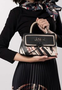 Borsa strutturata con una patta in pelle nera, caratterizzata da un motivo geometrico in beige e rosa. Include un manico superiore e dettagli metallici.