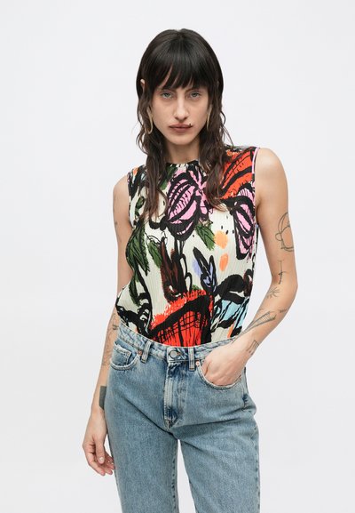 Αμάνικο τοπ σε κρεμ με ζωηρά λουλουδένια σχέδια σε κόκκινο, ροζ, πράσινο και μπλε; συνδυασμένο με ψηλόμεσο τζιν σε ανοιχτό μπλε.
