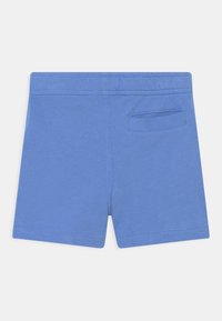 Pantalones cortos de algodón azules con una textura suave, que cuentan con un bolsillo trasero y costuras reforzadas. Diseño simple sin patrones ni adornos.
