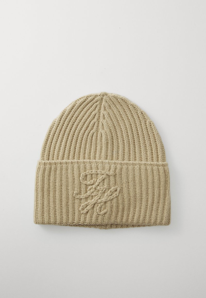 Strikket beige lue med vertikale ribber, oppbrettet kant og broderte logo detaljer, med en myk, teksturert finish.