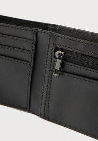 Εσωτερικό μαύρου δερμάτινου πορτοφολιού με θήκες για κάρτες και φερμουάρ. Λείος υφής με διακριτικές ραφές. Συμπαγής και λειτουργικός σχεδιασμός.