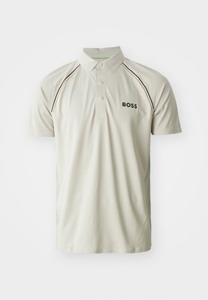 Kortermet polo skjorte i lys beige, med knappestolpe, perforert krage og svart logo med kontraststing.