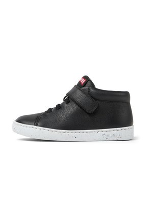 Zapatilla alta de cuero negro con tira de velcro, punta redondeada y suela de goma blanca moteada.
