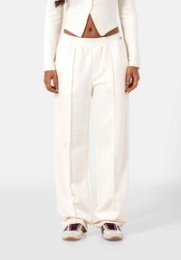 Crème kleurige wijde pantalon gemaakt van zachte stof, met plooien en een elastische tailleband. Gepaard met textuursneakers.