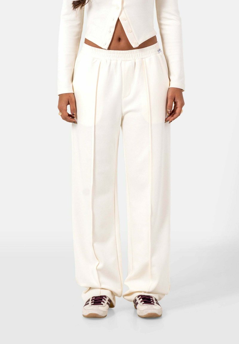 Crème kleurige wijde pantalon gemaakt van zachte stof, met plooien en een elastische tailleband. Gepaard met textuursneakers.