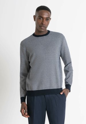 Suéter de rayas en navy y blanco de punto suave con cuello redondo. Puños y bajo acanalados. Combinado con pantalones oscuros.