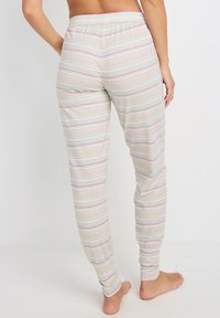 Pantalones de pijama ligeros a rayas en un suave beige con finas rayas horizontales en azul y rosa. Cintura elástica y puños ajustados. Sin bolsillos.