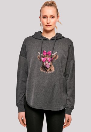 Grauer Hoodie mit lockerer Passform, mit einem Cartoon-Kuh-Graphic, die pinke Sonnenbrille und eine Schleife trägt, samt einem Lollipop-Detail.