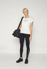 Hvit T-skjorte med svart logo, svarte leggings med sidelengde, svarte treningssko, og en svart treningsbag. Minimalistisk design.