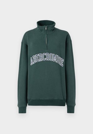 Sweatshirt vert avec un col montant et une demi-fermeture éclair, affichant le texte arrondi "ABERCROMBIE" en broderie blanche et marine sur la poitrine.