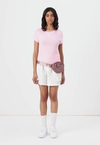 Lys rosa tettskjorte, hvite cargo-shorts med lommer, lys rosa belteveske, hvite sokker og sneakers. Enkelt og uformelt design.
