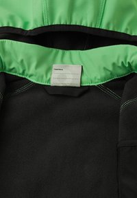 Intérieur d'une veste en polaire noire avec un revêtement vert. Les caractéristiques incluent des coutures contrastantes et une étiquette avec le texte "J'étais là".
