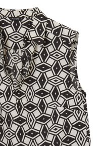 Blusa senza maniche a motivo geometrico bianco e nero con colletto e piccola tasca frontale, taglia piccola, etichettata Calliope.