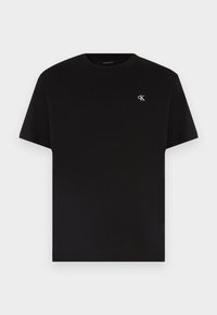 Camiseta negra de manga corta y cuello redondo con pequeño logo blanco "cK" en el lado izquierdo del pecho, diseño liso, presentada sobre fondo blanco.