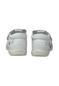 Scarpe in pelle bianca con una texture liscia, con dettagli a forma di stella argentata e suola in gomma flessibile. Nome del marchio "Primigi" impresso sul retro.