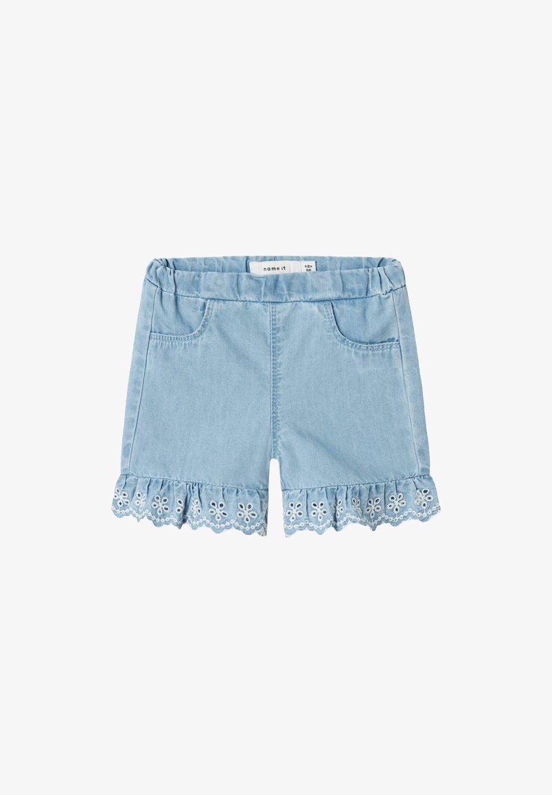 Vaaleansiniset farkkushortit, joissa on röyhelöhelma ja valkoista kukkaembroideryä, joustava vyötärö ja kaksi etutaskua.