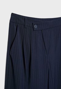 Navy gestreifte Hosen mit gefaltetem Vorderteil, einem einzelnen Knopfverschluss und einer glatten Textur mit dezenten kontrastierenden Nadelstreifen.