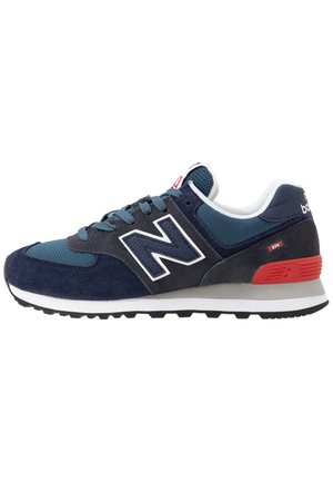 Baskets New Balance 574 bleu marine et gris avec accents rouges au talon, semelle intermédiaire blanche, semelle extérieure noire et tige en mesh et daim.
