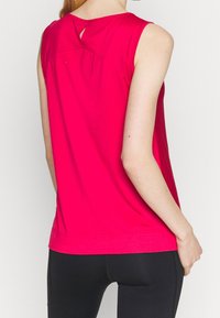 Fuchsiový bezramínkový top s kulatým výstřihem, detailem ve tvaru klíčové očko na zadní straně a volnějším střihem, vyrobený z měkké, lehké tkaniny.