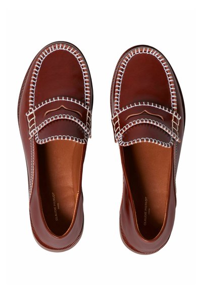 Mocasines de cuero marrón con detalles de costura blanca, punta redonda, textura suave y forro interior de cuero, con diseño sin cordones.