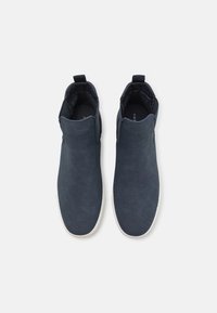 Námořnické kotníkové boty z hladkého materiálu s elastickými panely a poutkem, s bílou gumovou podrážkou pro kontrast.