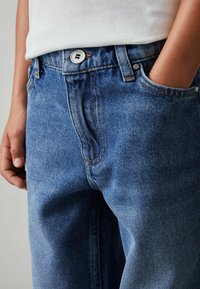 Modré džíny z denimu s volným střihem, designem pěti kapes, viditelnými švy a stříbrným knoflíkem na zapínání v pase.