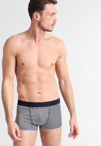 Pruhované boxerky v navy a bílé barvě, s pevným námořnickým pasem se znakem. Blízký střih vyrobený z měkkého materiálu.