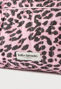 Odejena rožnata tkanina z vzorcem črnega leoparda. Ima bel napis na dnu, na katerem piše "lolly's laundry COPENHAGEN".