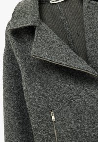 Grijze wolmix jas met een brede kraag, gestructureerd oppervlak en een asymmetrische ritssluiting aan de voorkant.