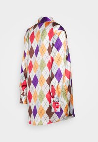 Camisa de mangas compridas com padrão em diamante nas cores vermelho, laranja, roxo, verde e castanho, sobre um fundo branco. Textura semelhante a cetim com punhos abotoados.