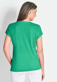 Groen T-shirt met korte mouwen, gemaakt van zachte stof, met een relaxte pasvorm en een ronde halslijn, getoond vanaf de achterkant tegen een witte achtergrond.